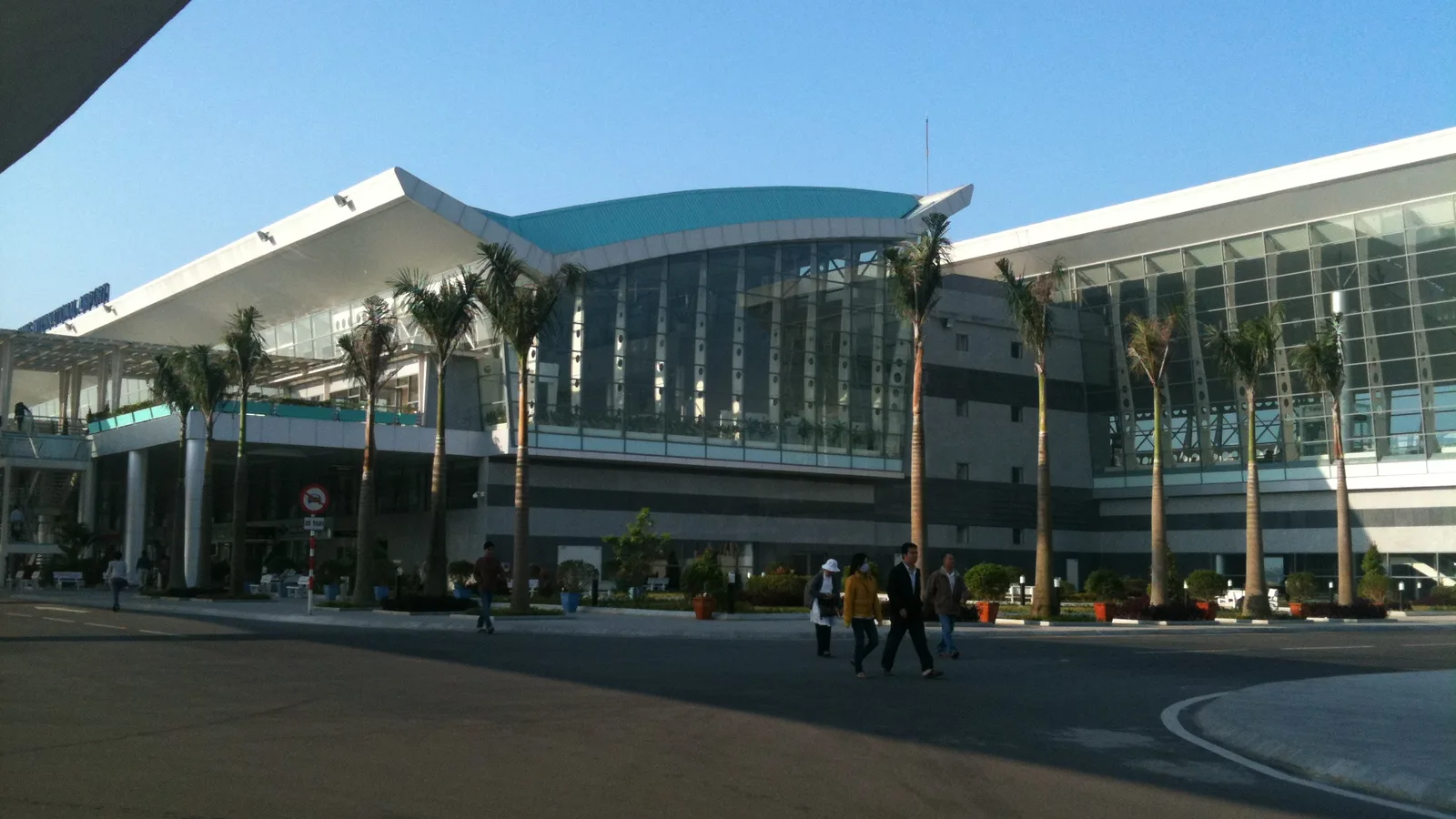 The glass-fronted terminal building at Da Nang International Airport with palm trees in front