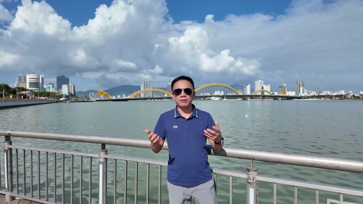 Mai Tien Tan beside the Han River in Da Nang, with the Dragon Bridge behind, on a clear January afternoon