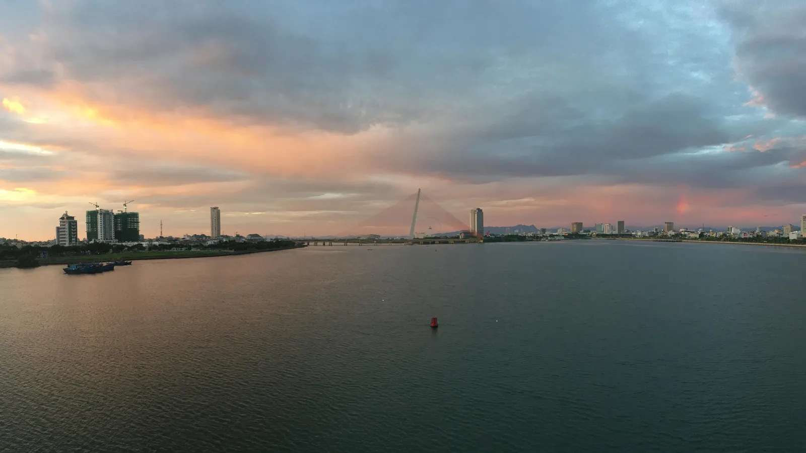 The Han River in Da Nang at sunrise under a cloudy pink sky, seen from the Dragon Bridge