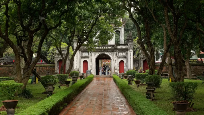 A brick path leading to the main gate of the Temple of Literature in Hanoi, under old trees
