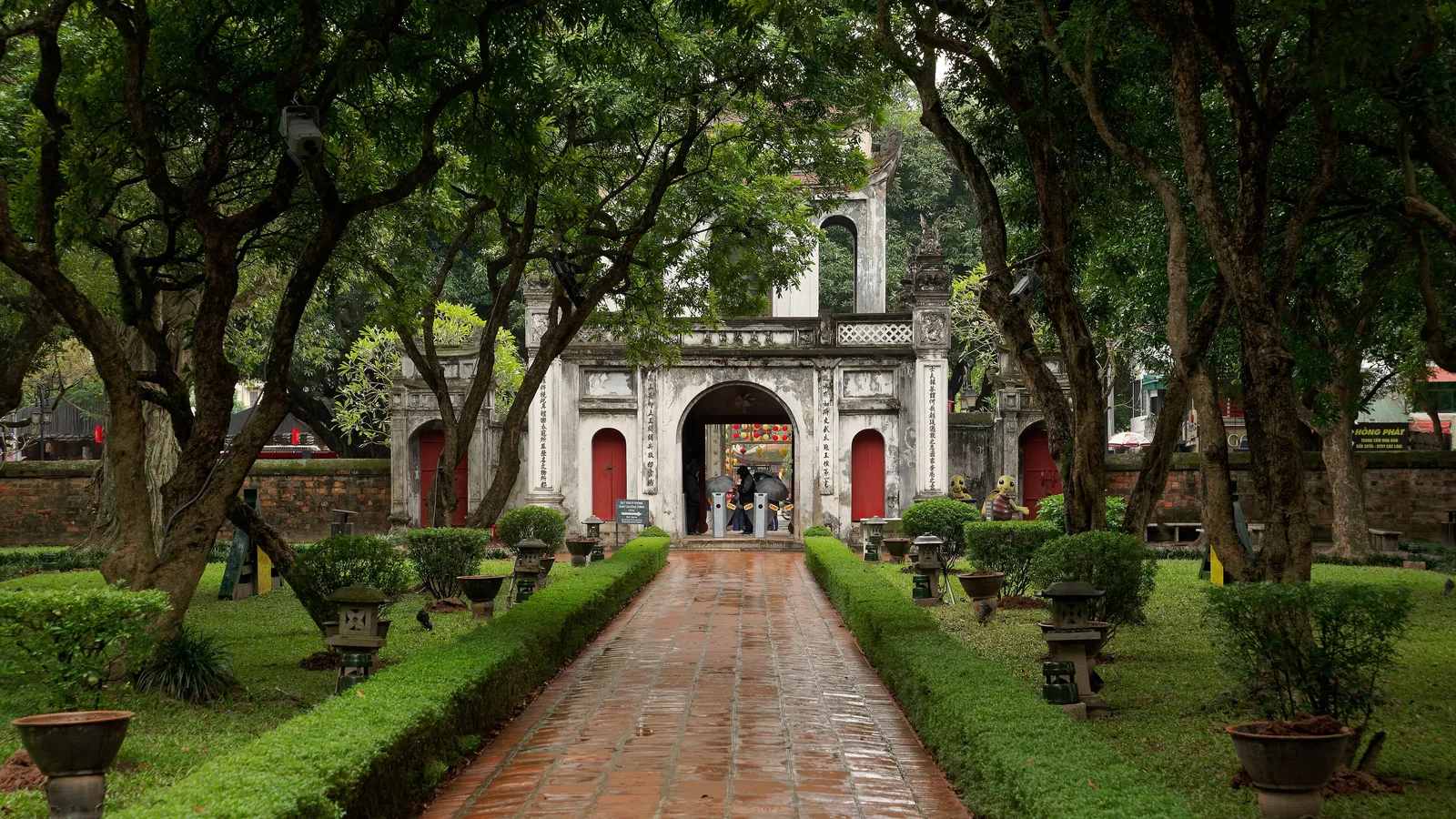 A brick path leading to the main gate of the Temple of Literature in Hanoi, under old trees