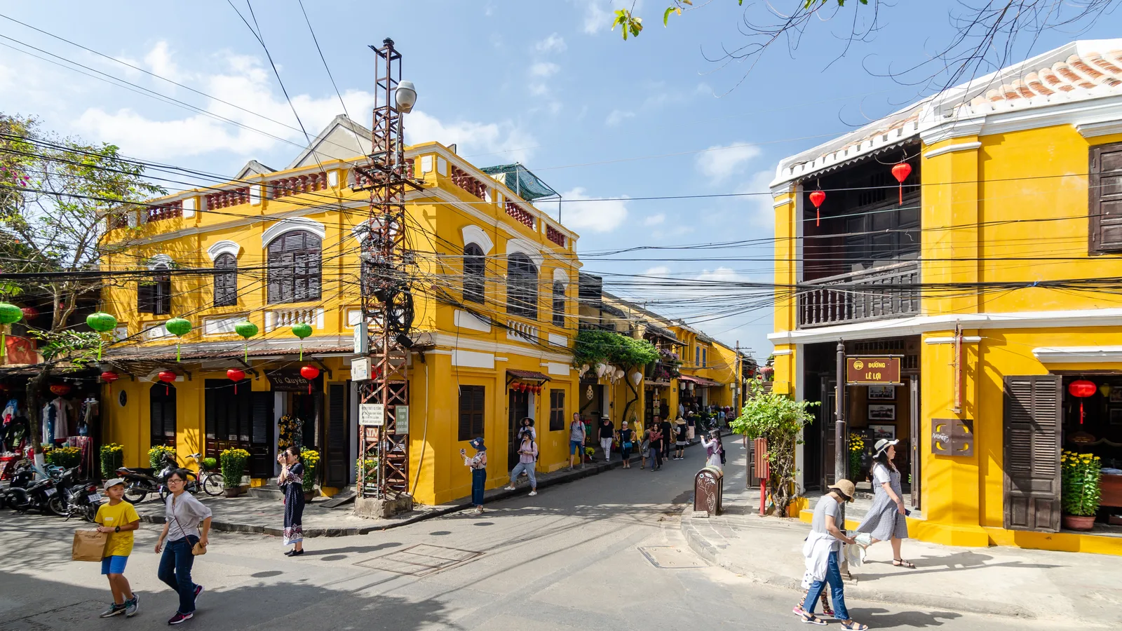 A street corner of yellow old buildings in Hoi An Ancient Town with pedestrians crossing