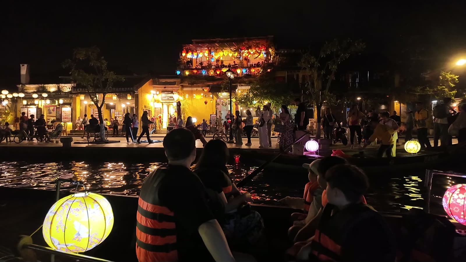 The Thu Bon river at Hoi An at night, with the lantern-lit waterfront reflected in the water