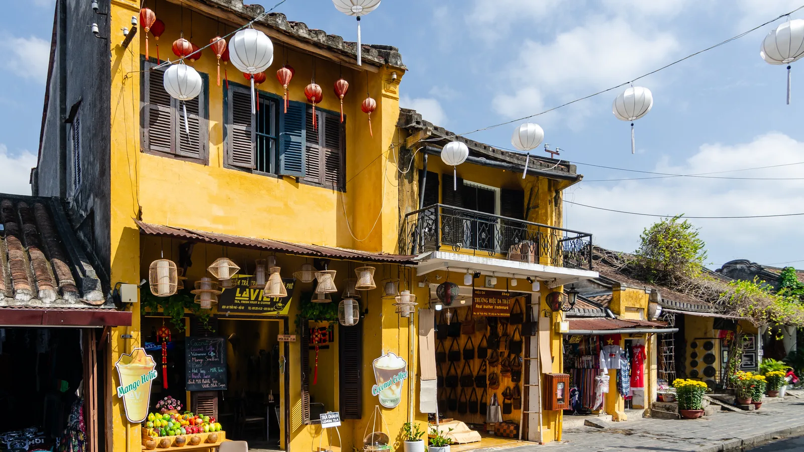 Yellow shophouses with white lanterns and small shops in Hoi An Ancient Town
