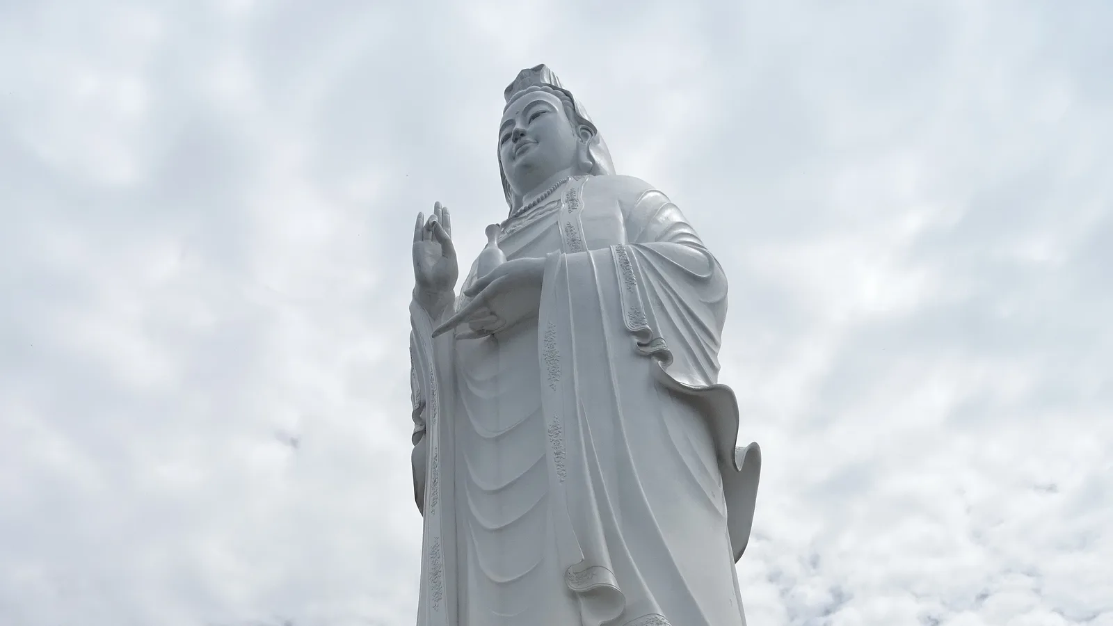 The white Lady Buddha statue at Linh Ung Pagoda on the Son Tra Peninsula, seen from below against cloud